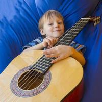 little boy plays guitar and sings on the balcony photo