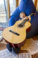 little boy plays guitar and sings on the balcony photo