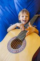 little boy plays guitar and sings on the balcony photo