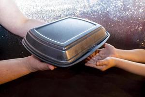 food delivery coronavirus. a black lunch box to pass from hand to hand. polypropylene black boxes for food delivery. photo