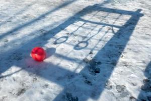 red ball in the snow on the background of the shadow of the rings photo