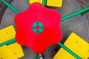 un elemento de un columpio para niños. volante . un colorido parque infantil al aire libre junto a la casa. un dia de verano parque infantil con suelo de goma. foto