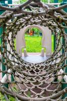 Inside view of a long rope mesh pipe, at the end of the tunnel yellow playground blurred background photo