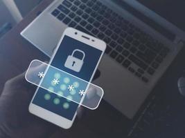 Cybersecurity essentials on smartphones. Digital cyber crime by anonymous hackers. Men hand holding a phone on a laptop with 3d icons password for personal data security and finance. photo