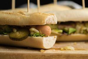 Hot Dogs with sausage, cucumber, lettuce and roasted onion on a wooden board, homemade photo