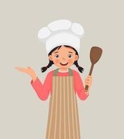 linda niñita con sombrero de chef y delantal sosteniendo una espátula de utensilio de cocina con la mano mostrando espacio para copiar vector