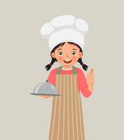 cute little girl in chef hat and apron holding a tray showing thumb up
