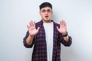 Young handsome asian man moving away hands palms showing refusal and denial with afraid and disgusting expression. Stop and forbidden. photo