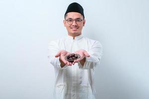 Asian muslim man holding dates fruit showing it to forward photo