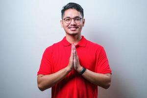 Young Asian man wearing casual shirt with greeting and welcoming gesture photo