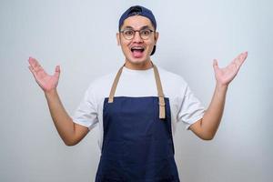 Young handsome asian barista man wearing apron smiling confident showing both hands open palms, presenting and advertising comparison and balance photo