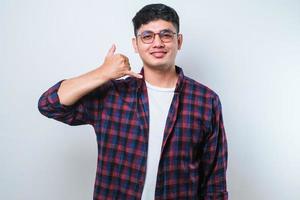 Young asian smiling doing phone gesture with hand and fingers like talking on the telephone. Communicating concepts. photo