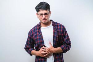 joven asiático con dolor de estómago o dolor abdominal problema de salud malestar diarrea aislado foto