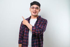 Young handsome asian man pointing with hand finger to the side looking at the camera. photo
