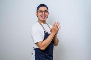 Young asian barista man wearing apron  clapping and applausing happy and joyful, smiling proud hands together photo