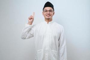 Asian muslim man wearing casual clothes showing and pointing up with fingers number one while smiling confident and happy photo