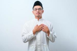 Asian muslim man wearing casual clothes smiling with hands on chest with closed eyes and grateful gesture on face photo