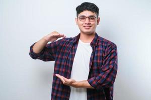 Handsome asian man gesturing with hands showing big and large size sign, measure symbol. smiling looking at the camera. measuring concept. photo