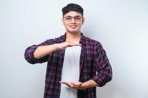 Handsome asian man gesturing with hands showing big and large size sign, measure symbol. smiling looking at the camera. measuring concept. photo