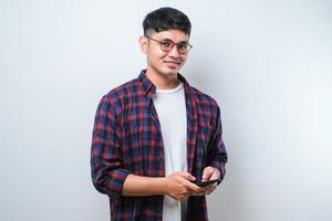 Smiling young good looking Asian man using smartphone to get in touch with family and friends photo