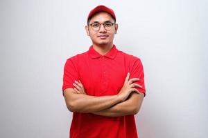 Close-up of confident smiling asian male courier in red uniform and cap, smiling determined, cross arms chest photo