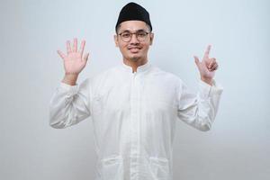 Asian muslim man wearing casual clothes showing and pointing up with fingers number seven while smiling confident and happy photo