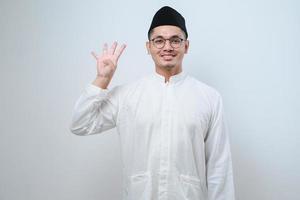 Asian muslim man wearing casual clothes showing and pointing up with fingers number four while smiling confident and happy photo