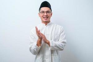 Smiling Asian Muslim man clapping in hands and looking at camera isolated photo
