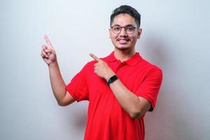 Young handsome asian man wearing casual shirt  pointing something on his side with his both hands photo