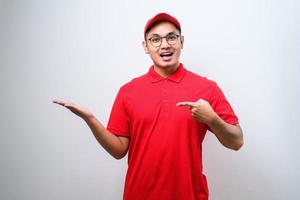 un joven y apuesto repartidor chino señalando con la mano y el dedo a un lado mirando la cámara. foto