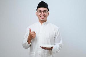 Asian muslim man showing excited expression while holding empty dinner plate photo