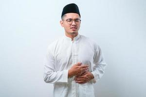 Asian muslim man squezze his stomach for having stomachache pain photo