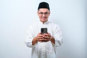 Handsome young asian man wearing muslim clothing making video call using mobile phone photo