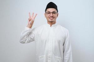 Asian muslim man wearing casual clothes showing and pointing up with fingers number three while smiling confident and happy photo