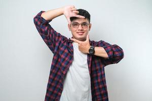 Young handsome asian boy smiling making frame with hands and fingers with happy face. Creativity and photography concept photo