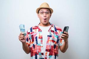 Asian young man showing wow face expression while holding mobile phone and paper money photo