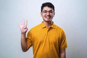 Asian young man showing and pointing up with fingers number four photo