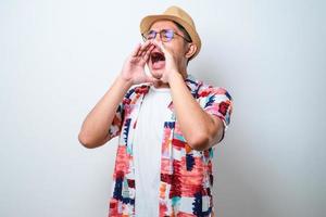 Young asian man shouting and screaming loud to side with hand on mouth photo