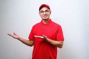 un joven y apuesto repartidor chino señalando con la mano y el dedo a un lado mirando la cámara. foto