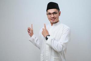 Asian muslim mas pointing something on his side with his both hand photo