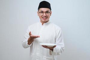 Asian muslim man showing excited expression while holding empty dinner plate photo