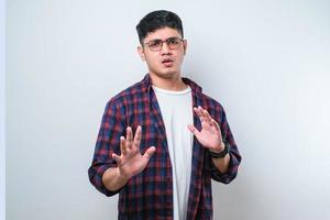 Young handsome asian man moving away hands palms showing refusal and denial with afraid and disgusting expression. Stop and forbidden. photo
