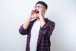 joven asiático gritando y gritando fuerte a un lado con la mano en la boca foto