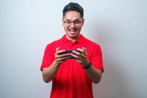 Portrait of young Asian man wearing casual shirt playing online game on mobile phone photo