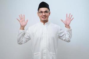 Asian muslim man wearing casual clothes showing and pointing up with fingers number ten while smiling confident and happy photo
