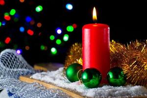 Red candle with a green New Year's ball on the background of lights photo