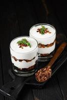 Greek yogurt with granola on a wooden dark wooden background. photo