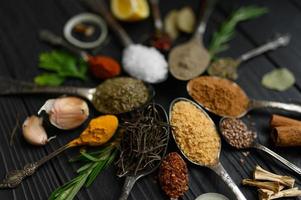 Colorful various herbs and spices for cooking on dark wooden rustic background photo