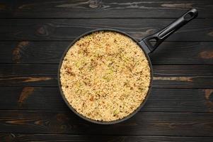 Fried rice with onions and zucchini in a pan on a rustic wooden background. photo