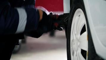 Mecánico de automóviles desenroscando la rueda del coche del pasador del automóvil en servicio video